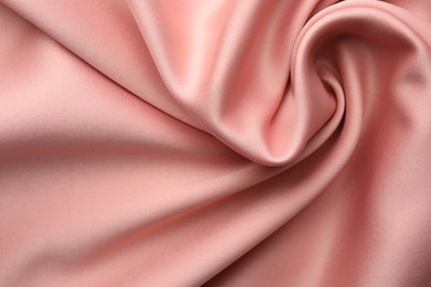 Crumpled pink silk fabric as background, top view