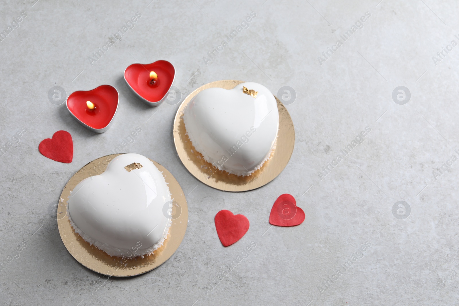 Photo of St. Valentine's Day. Delicious heart shaped cakes, candles and confetti on light table, flat lay. Space for text