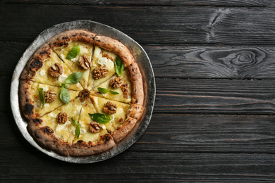 Delicious cheese pizza with walnuts on black wooden table, top view. Space for text