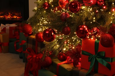 Many gift boxes under decorated Christmas tree and fireplace indoors