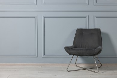 Photo of Comfortable armchair near grey wall in room, space for text