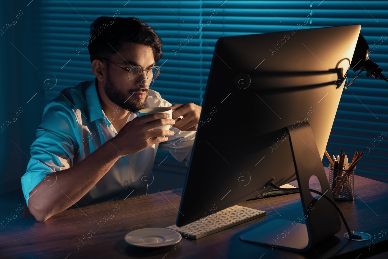 Photo of Tired man with coffee working late in office