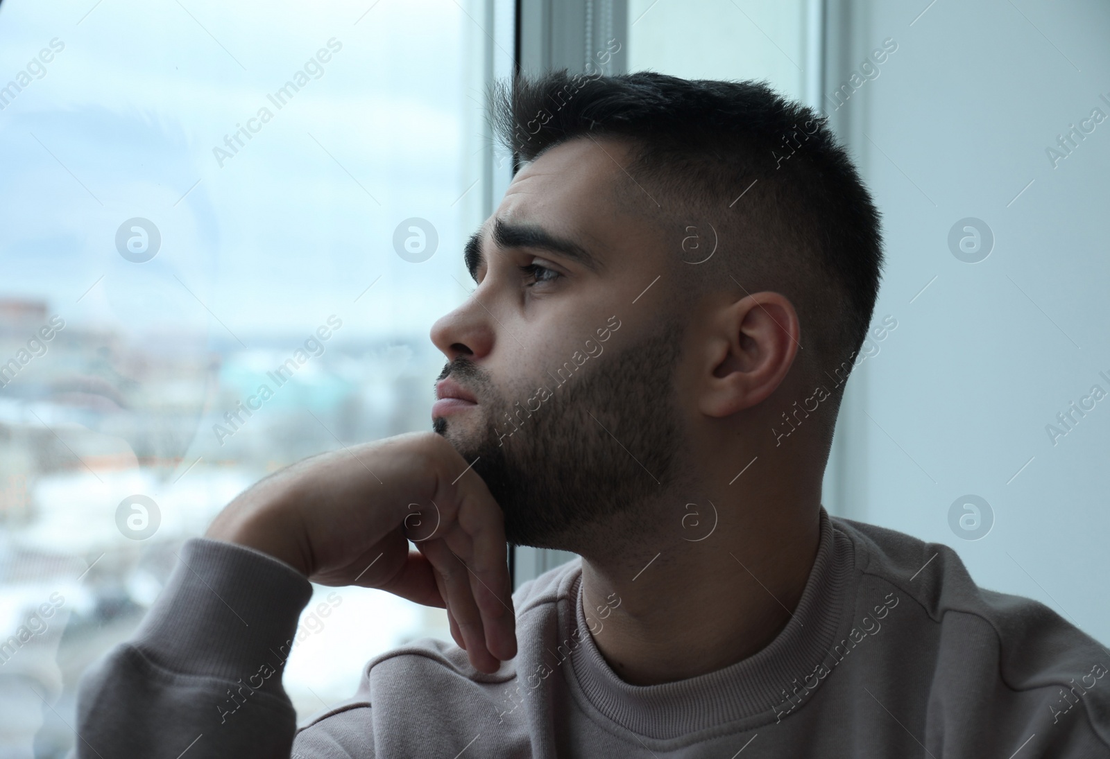 Photo of Portrait of sad man near window at home