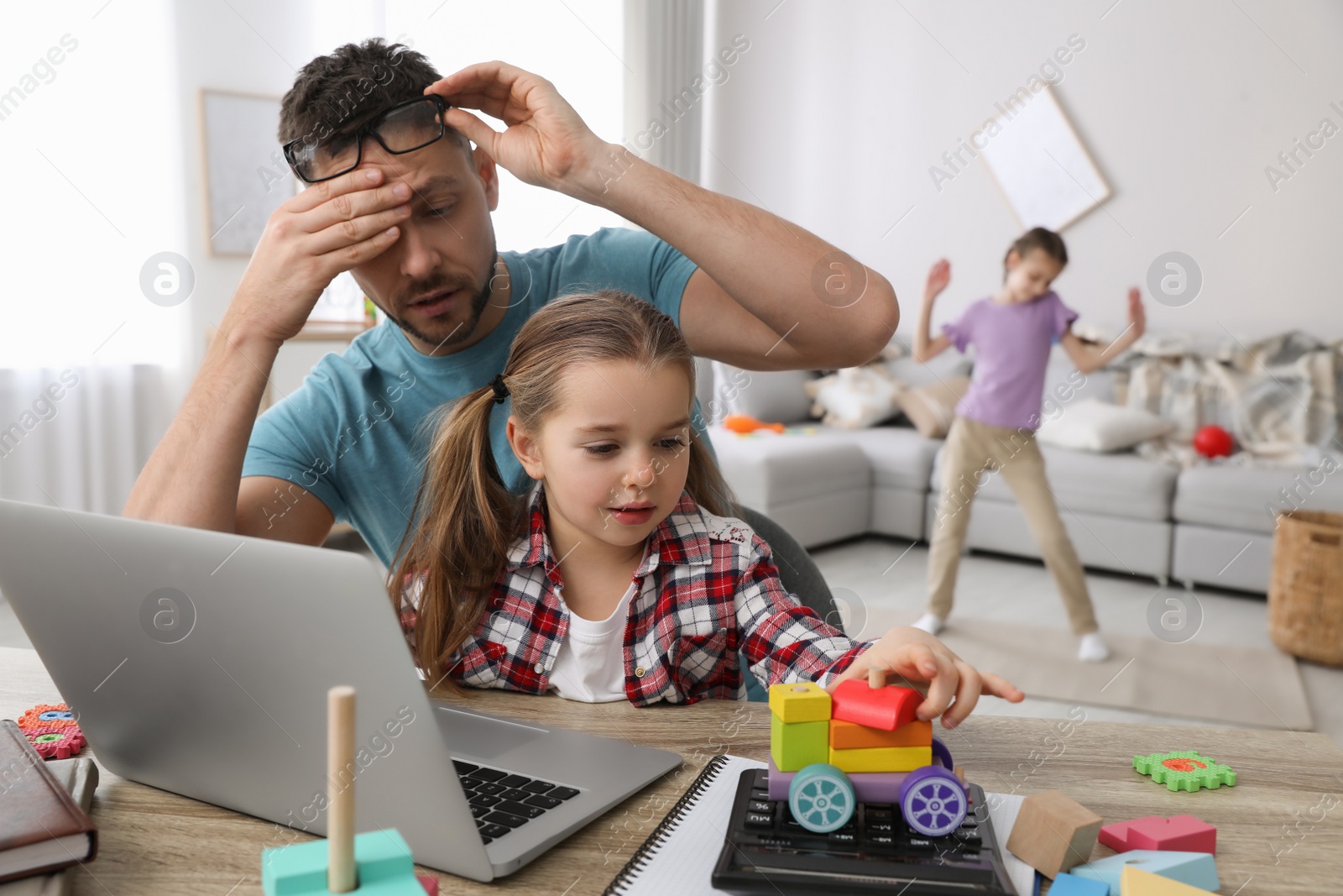 Photo of Children disturbing stressed man in living room. Working from home during quarantine