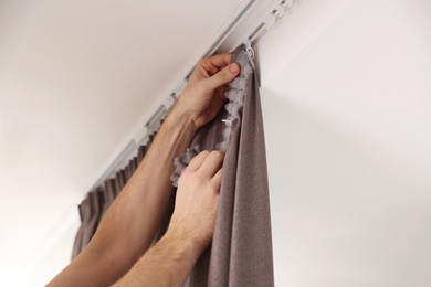 Worker hanging window curtain indoors, low angle view