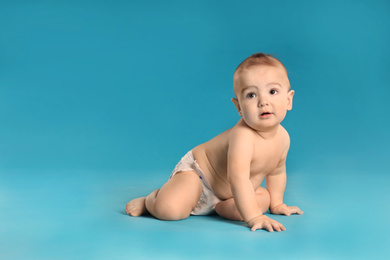 Cute little baby in diaper on light blue background. Space for text