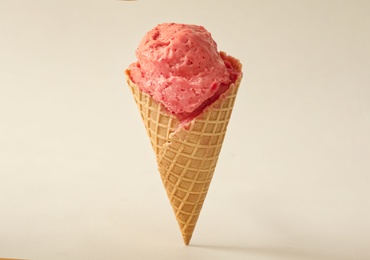 Delicious pink ice cream in waffle cone on white background