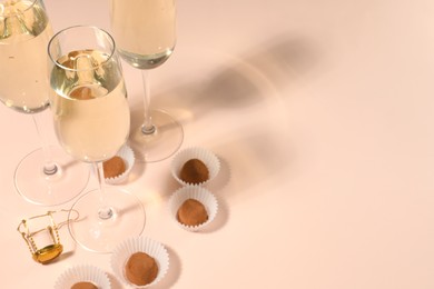 Photo of Glassesdelicious sparkling wine and chocolate truffles on pale pink background. Space for text