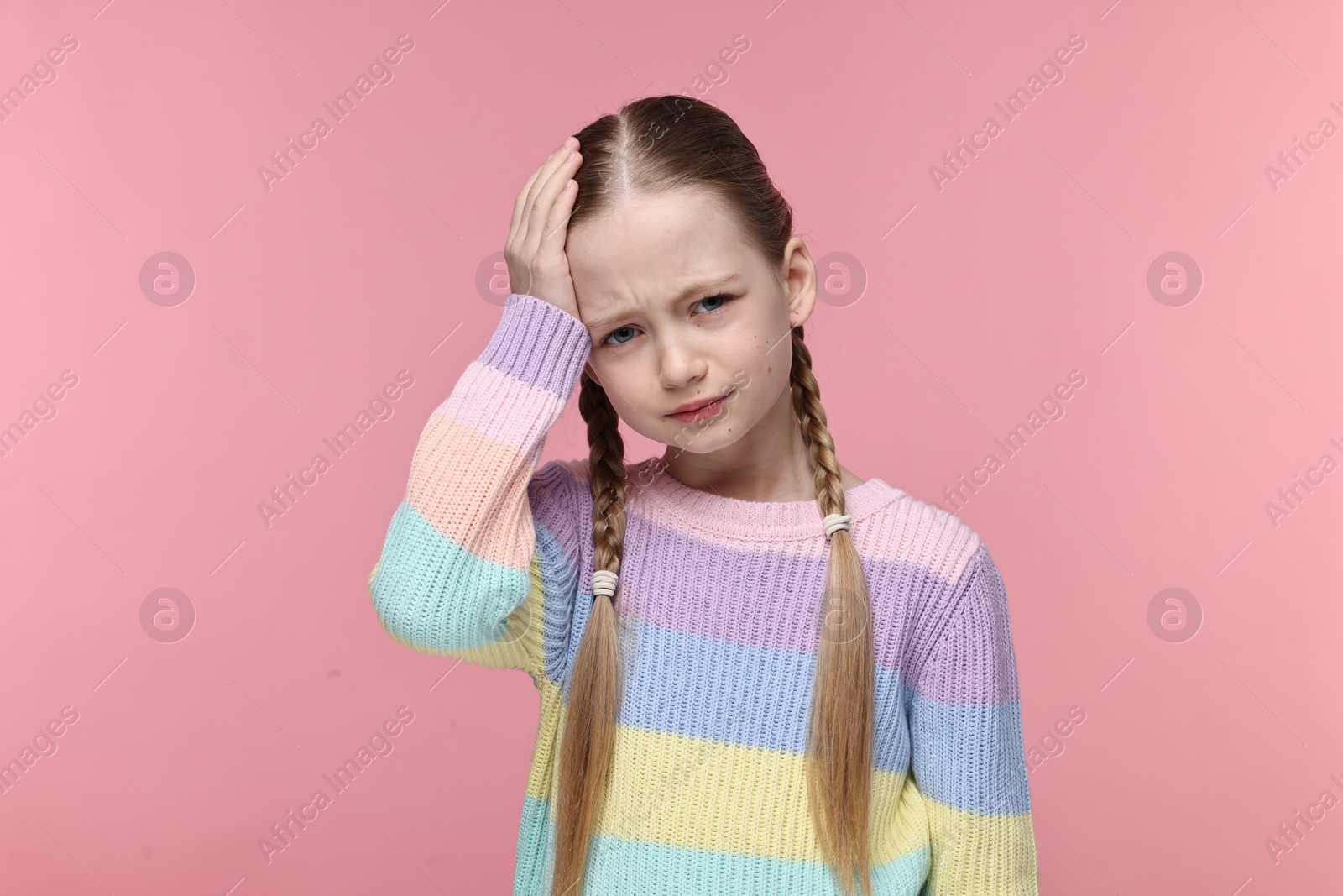 Photo of Little girl suffering from headache on pink background