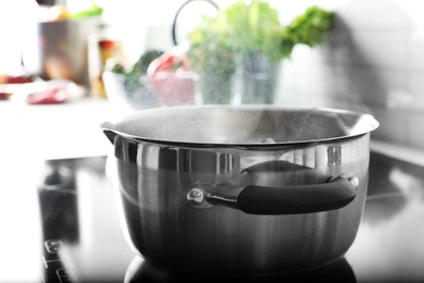 Photo of Pot with boiling water on electric stove in kitchen