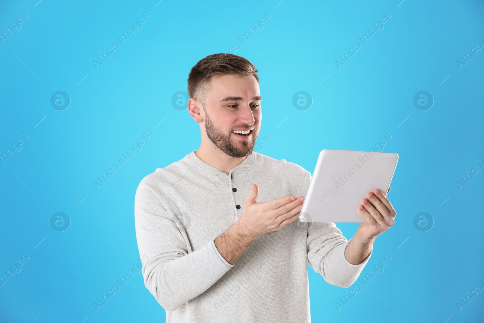 Photo of Young man using video chat on tablet against color background