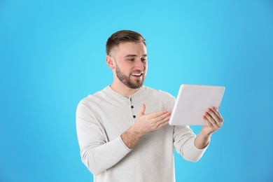 Photo of Young man using video chat on tablet against color background