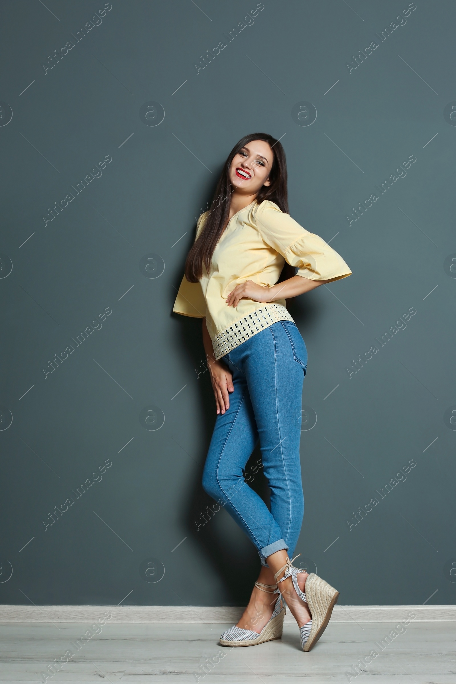 Photo of Full length portrait of beautiful woman with sexy legs near grey wall