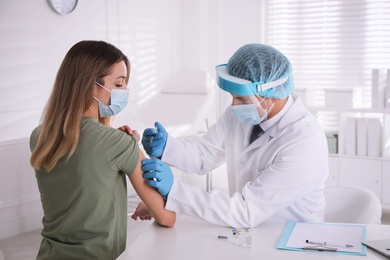 Doctor vaccinating young woman against Covid-19 in clinic
