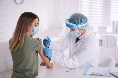 Photo of Doctor vaccinating young woman against Covid-19 in clinic