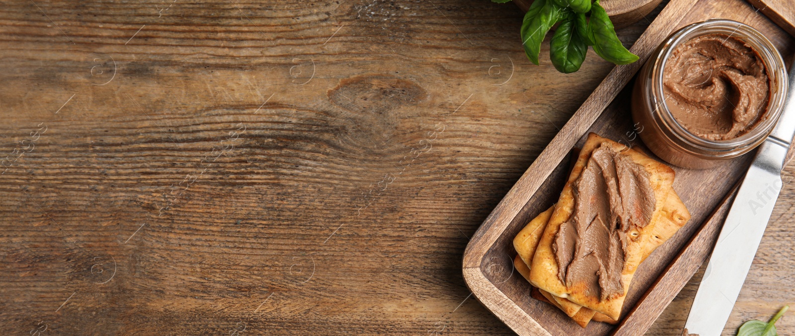 Image of Jar with delicious pate and crackers on wooden table, flat lay. Banner design with space for text