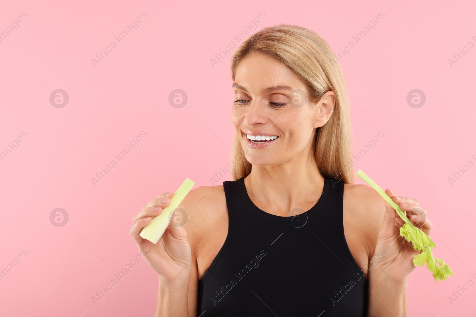 Photo of Woman with pieces of fresh celery stem on pink background