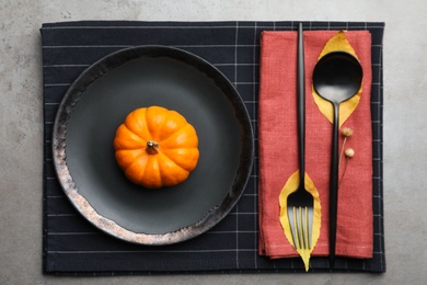 Photo of Seasonal table setting with pumpkin and autumn leaves on grey background, flat lay