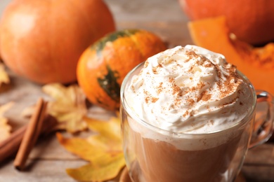 Photo of Glass cup with tasty pumpkin spice latte on table, closeup