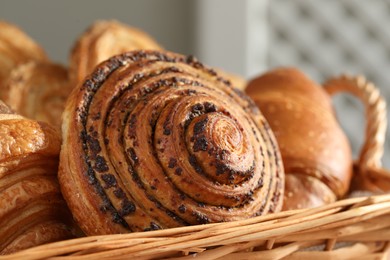 Photo of Tasty freshly baked spiral pastry in wicker basket, closeup