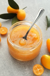 Photo of Delicious kumquat jam and fresh fruits on light grey table