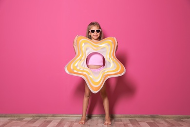 Photo of Cute little girl with bright star shaped inflatable ring near color wall