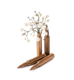 Photo of Bullets and cartridge case with beautiful gypsophila flowers isolated on white