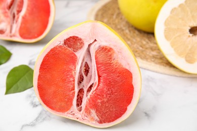 Different tasty pomelo fruits on white marble table, closeup