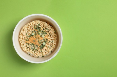 Photo of Cup of instant noodles on color background, top view. Space for text