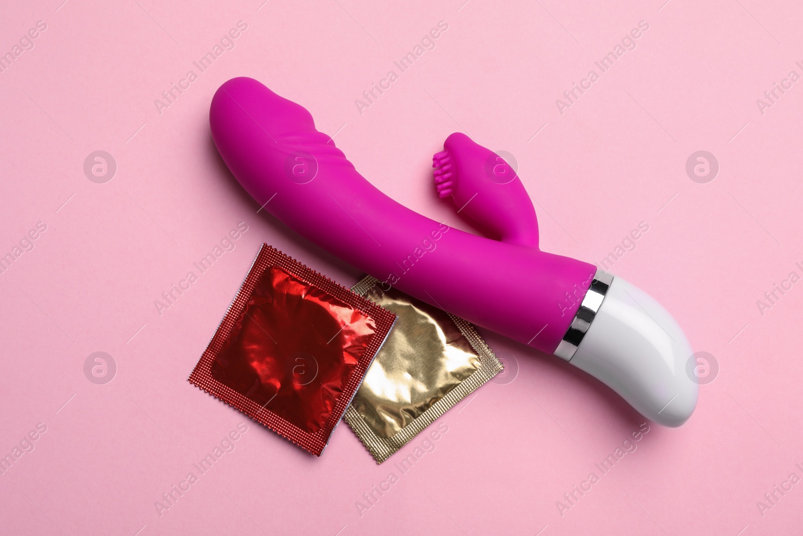 Photo of Vibrator and condoms on pink background, top view. Sex game
