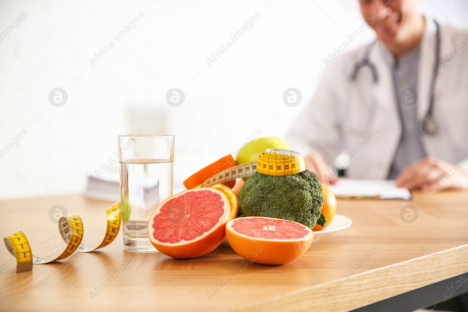 Photo of Healthy products, measuring tape and blurred nutritionist on background