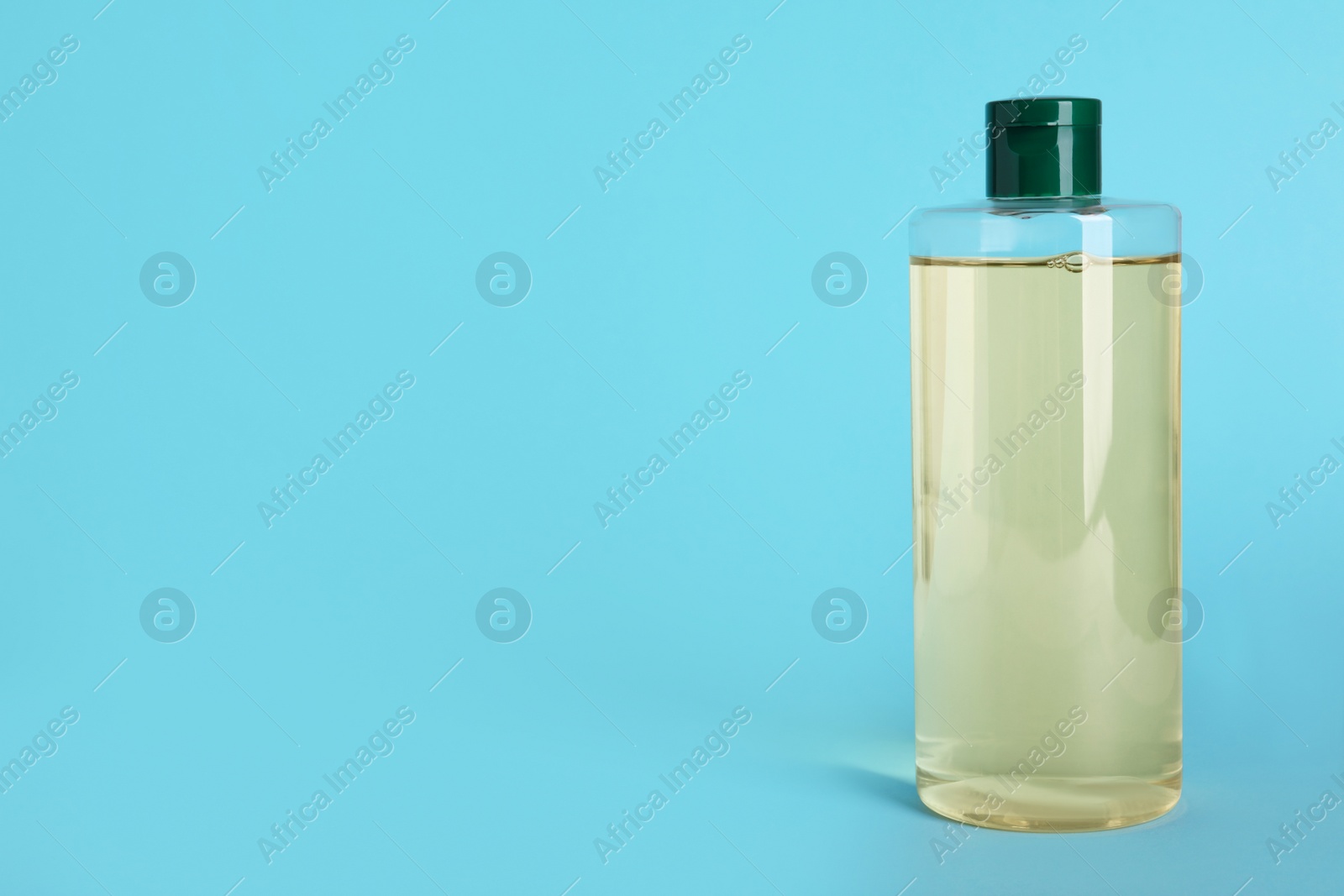 Photo of Bottle of micellar water on light blue background. Space for text