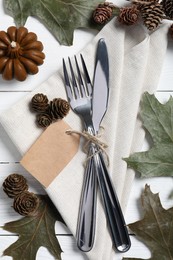 Photo of Thanksgiving day table setting. Cutlery, napkin and autumn decoration on white wooden background, flat lay