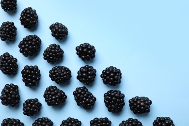 Photo of Tasty ripe blackberries on light blue background, flat lay. Space for text
