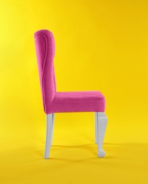 Photo of Stylish pink chair on yellow background. Element of interior design