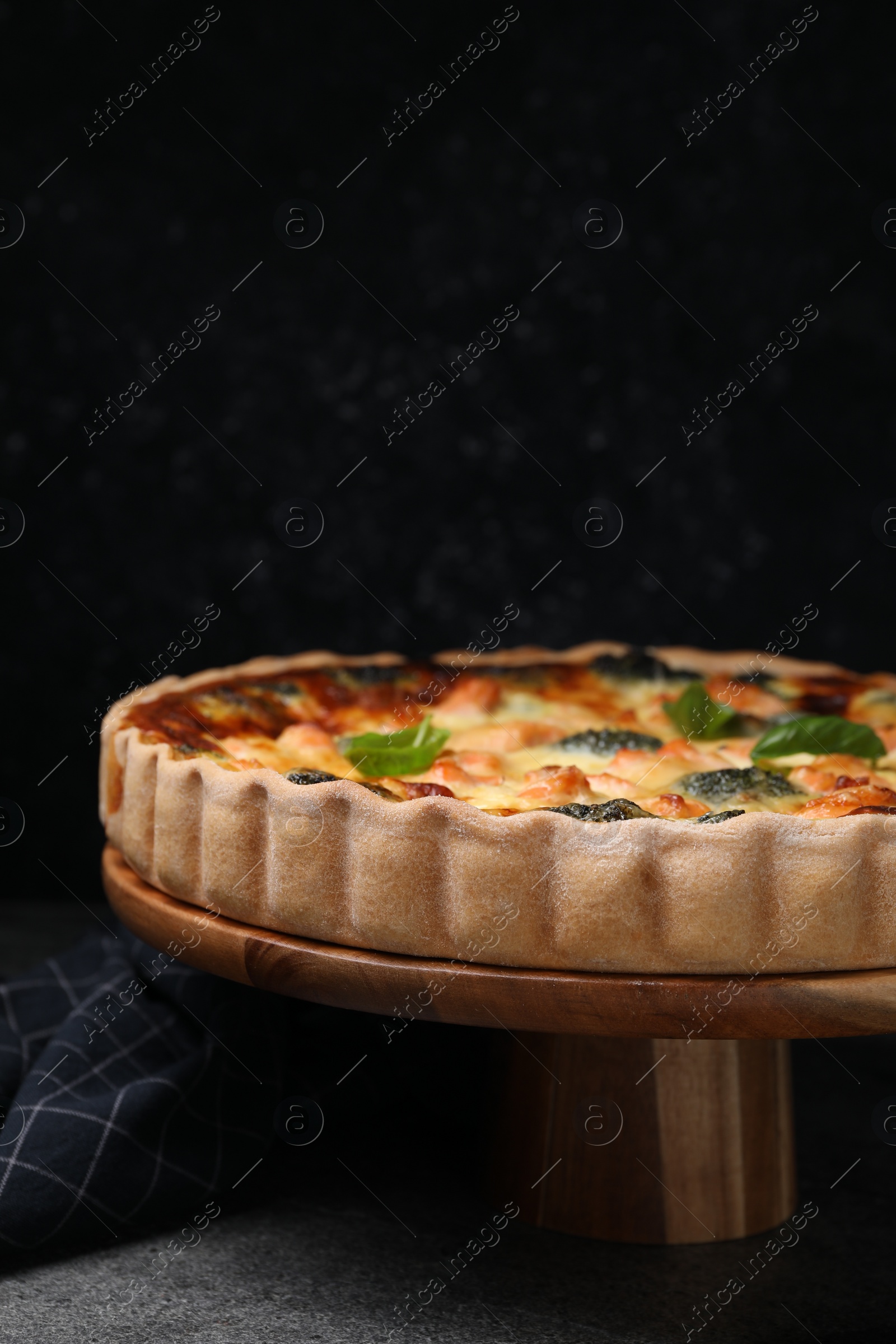 Photo of Delicious homemade quiche with salmon and broccoli on wooden stand