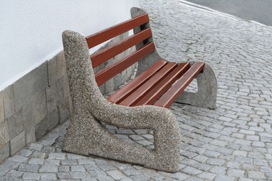 Photo of Wooden bench near building on pavement outdoors