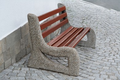 Wooden bench near building on pavement outdoors