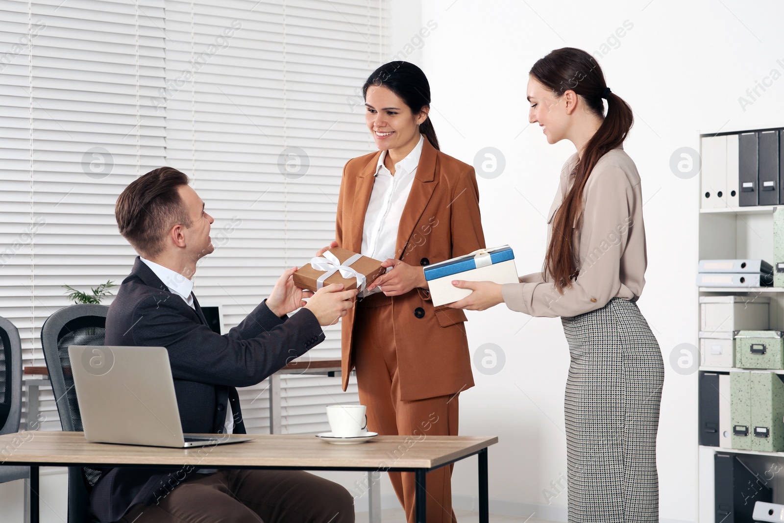 Photo of Colleagues presenting gifts to woman in office