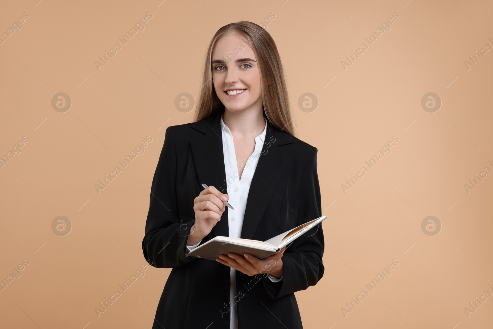 Photo of Happy young secretary with notebook and pen on beige background