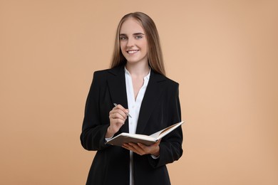 Photo of Happy young secretary with notebook and pen on beige background