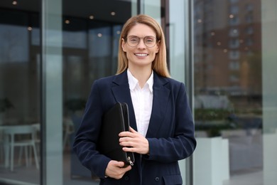 Photo of Female real estate agent with leather portfolio outdoors