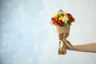 Photo of Woman holding bouquet of beautiful spring freesia flowers on color background. Space for text