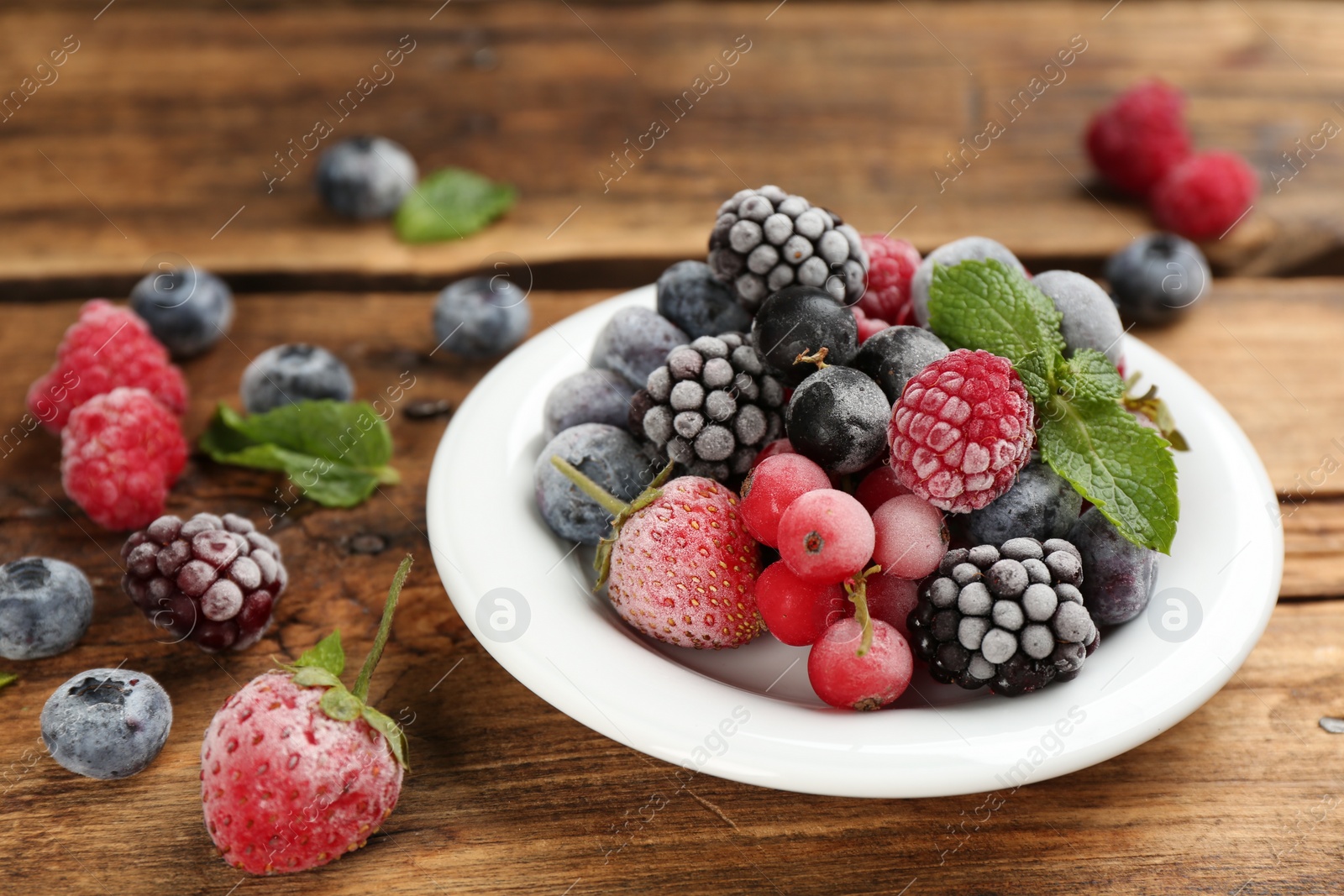 Photo of Mix of different frozen berries on wooden table, closeup