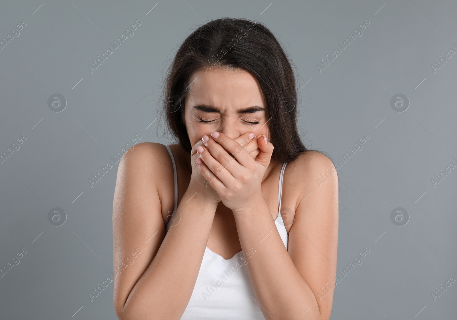 Photo of Young woman suffering from nausea on grey background. Food poisoning