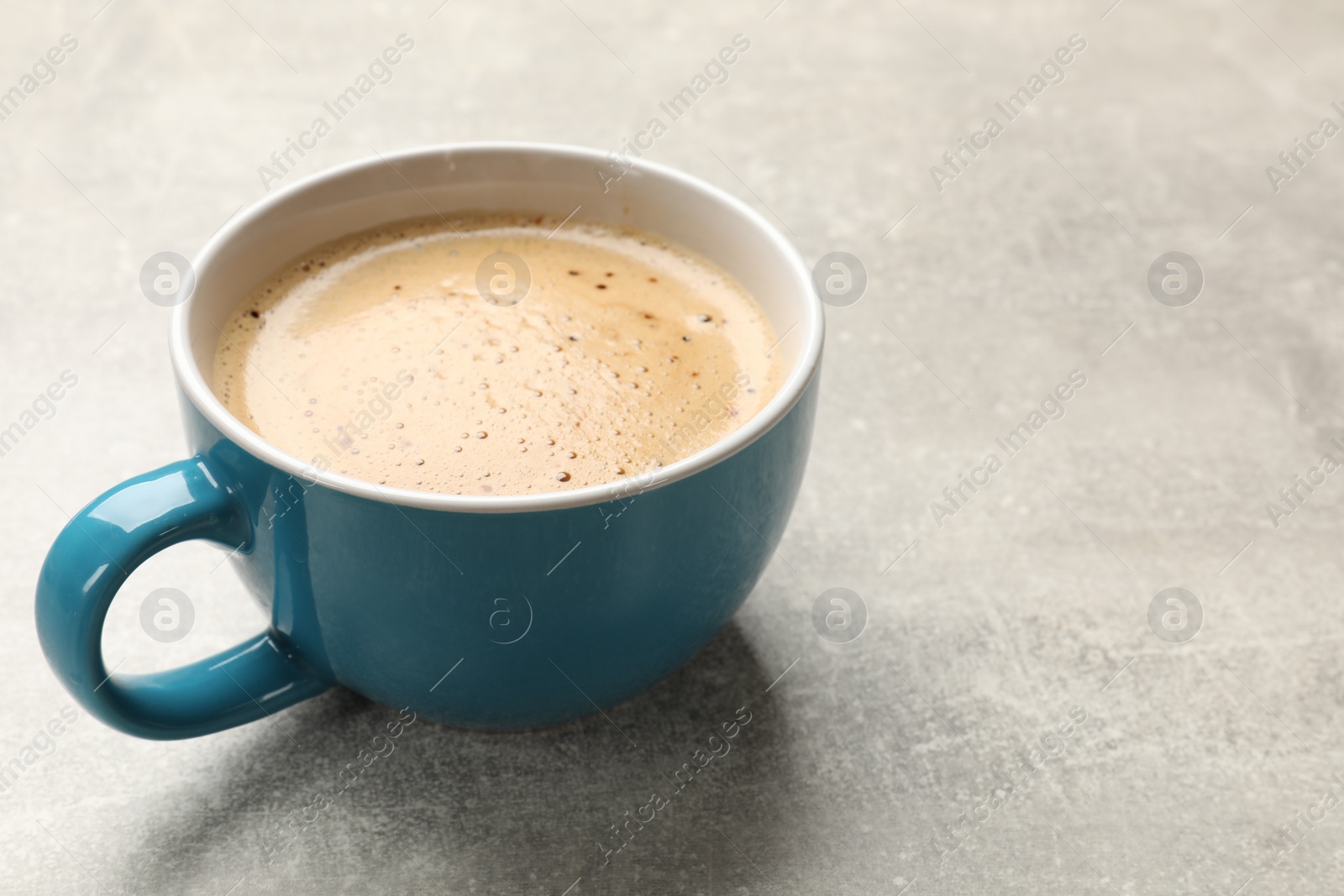 Photo of Cup of aromatic coffee on light grey table, closeup. Space for text