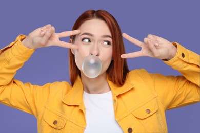 Photo of Beautiful woman blowing bubble gum and gesturing on purple background