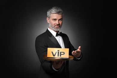 Photo of Handsome man holding tray with VIP sign on black background
