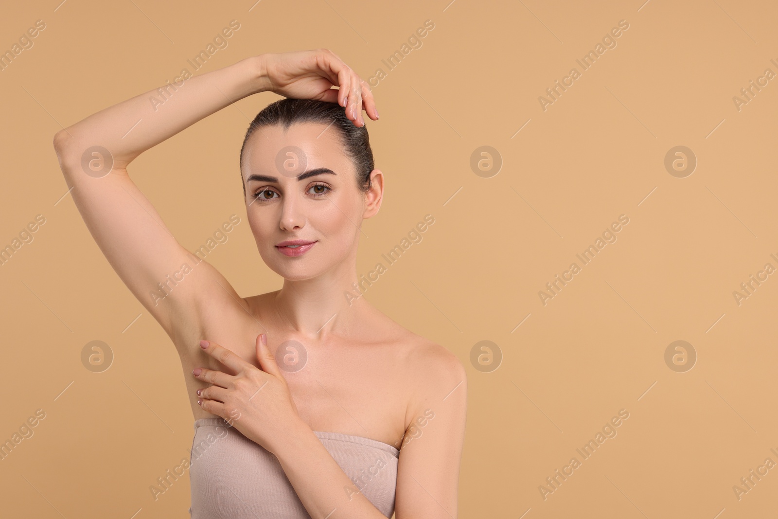 Photo of Beautiful woman showing armpit with smooth clean skin on beige background, space for text