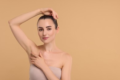 Beautiful woman showing armpit with smooth clean skin on beige background, space for text